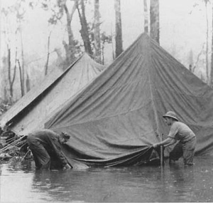 Marines attempt to shelter against a monsoon shower on Cape Gloucester