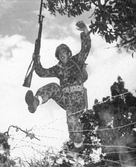 Photograph of Marine Raider charging a wire barrier in training