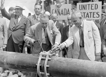 Photograph of
          pipeline being ceremonially joined at U.S.-Canada border,
          1941