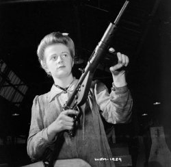 Photograph of factory worker with Sten
        submachine gun