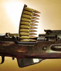 Ammunition being loaded into a rifle from a stripper clip